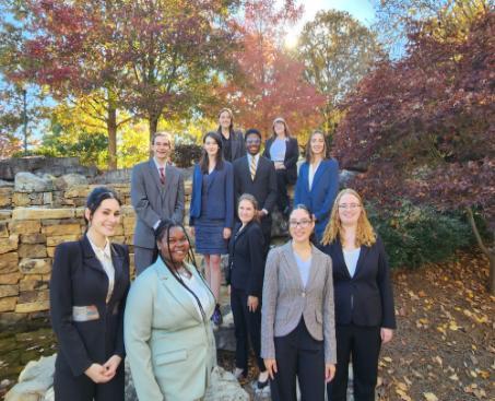 Eleven forensics team members posed for a group picture on Berry College's campus. The trees around them are red and orange at the beginning of fall.
