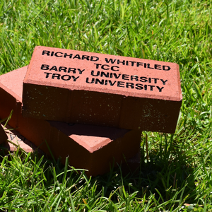 Brick on grass with the name of a donor carved into it